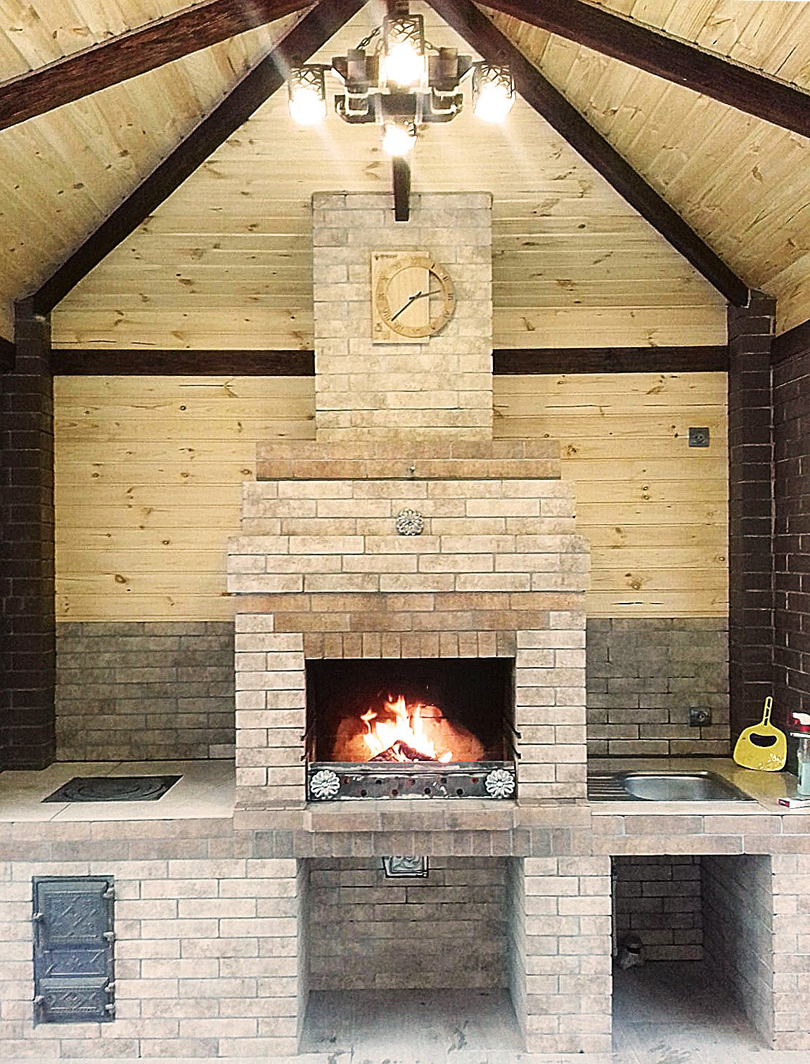 Grill ogrodowy wyłożony jest kamieniem naturalnym, płytkami ceramicznymi i elementami drewnianymi.