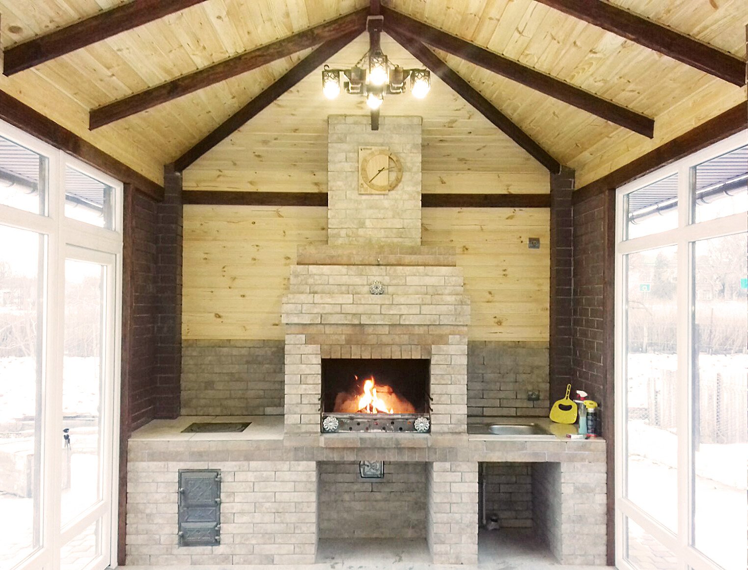 Grill ogrodowy wyłożony jest kamieniem naturalnym, płytkami ceramicznymi i elementami drewnianymi.