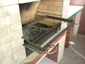 Grill ogrodowy wyłożony jest kamieniem naturalnym, płytkami ceramicznymi i elementami drewnianymi.