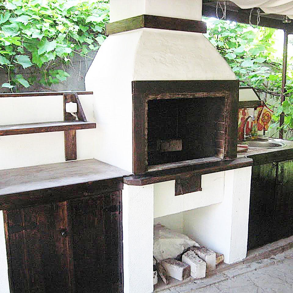 Grill ogrodowy jest otynkowany i pomalowany. Zawiera dekoracyjne elementy drewniane.