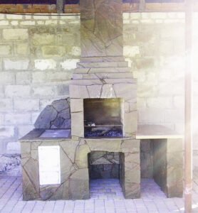 Grill ogrodowy wyłożony jest kamieniem naturalnym, płytkami ceramicznymi 
