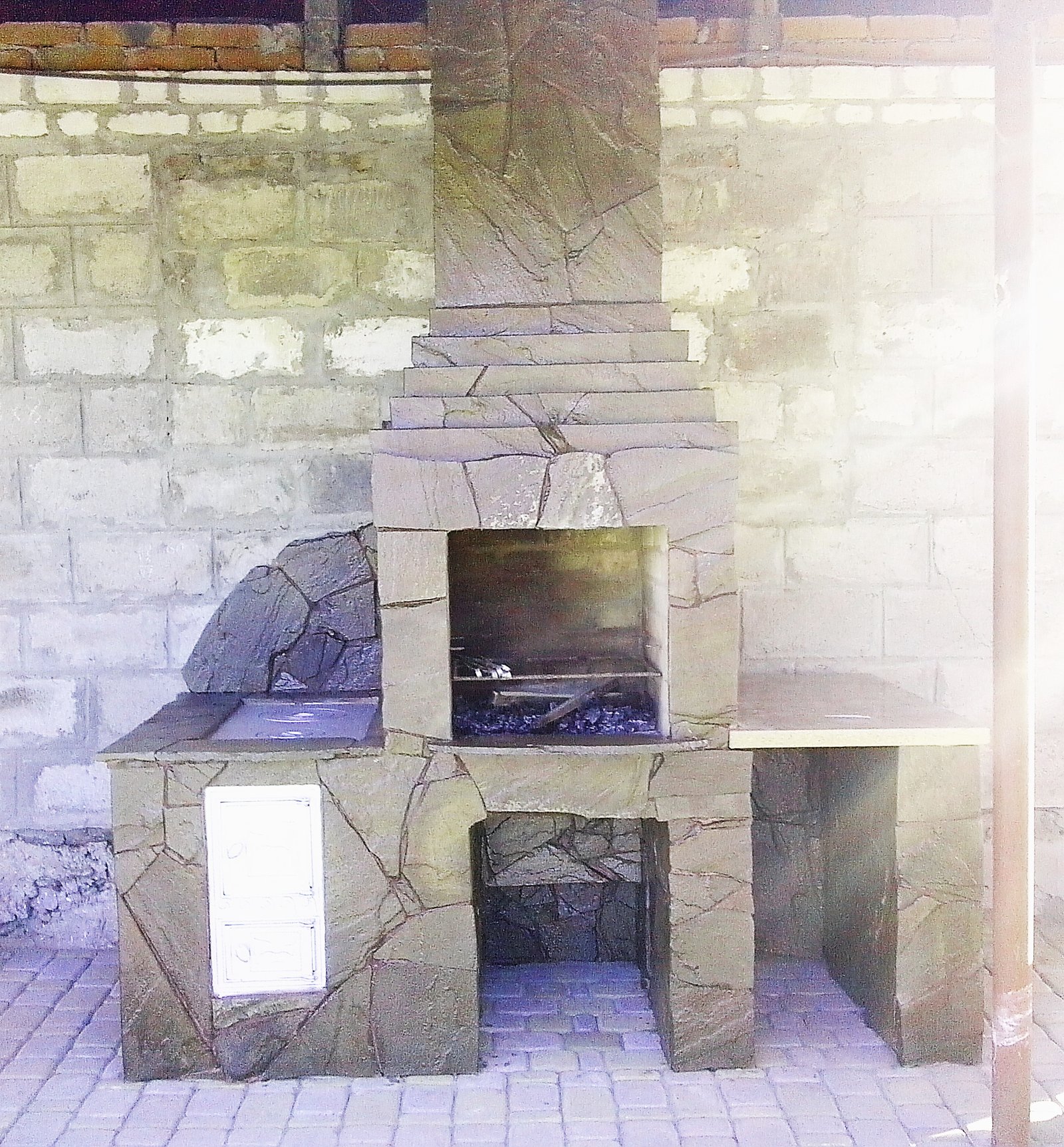 Grill ogrodowy wyłożony jest kamieniem naturalnym, płytkami ceramicznymi 