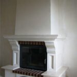 Kominek wykończony jest gipsowymi elementami dekoracyjnymi i pomalowany.