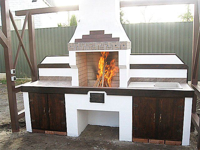 Grill ogrodowy jest otynkowany i pomalowany. Zawiera dekoracyjne elementy drewniane.