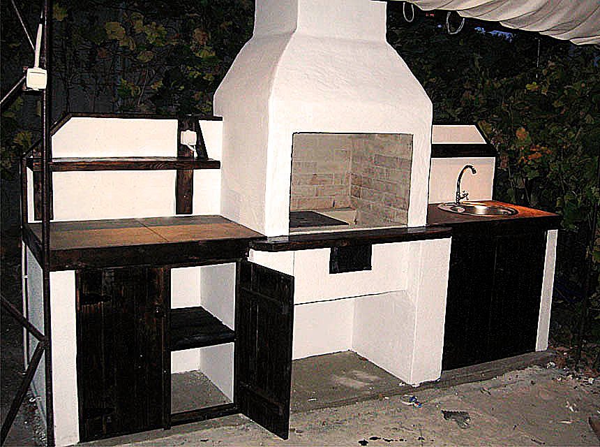 Grill ogrodowy jest otynkowany i pomalowany. Zawiera dekoracyjne elementy drewniane.